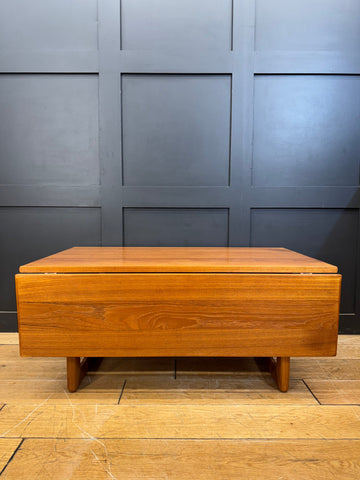 A sleek medium-toned teak wood drop leaf coffee table with smooth finish and tapered legs perfect for living spaces