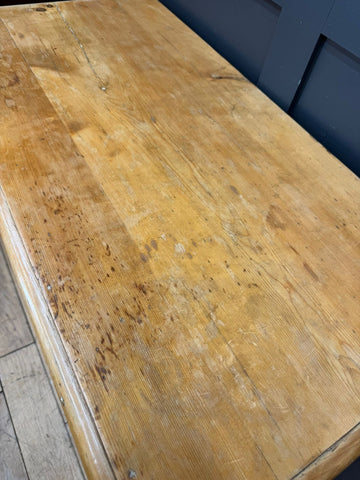 Mid victorian rustic pine chest with rounded corners on a well-worn light golden-brown wooden table surface