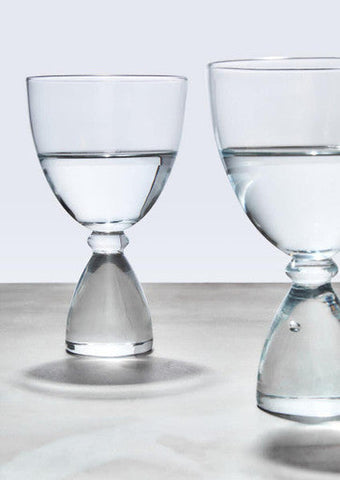 Mila set of 2 clear cocktail glasses with slender stems and hourglass-shaped base filled halfway with water
