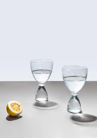 Two clear cocktail glasses with hourglass-shaped bases filled halfway with water in the mila set of 2 clear cocktail glasses