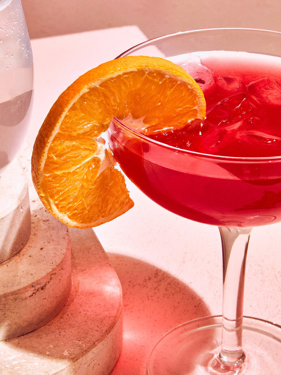A vibrant red cocktail in a mila set of 2 cocktail glasses 300ml with a bright orange slice garnish