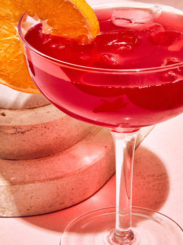 A vibrant red cocktail in a clear stemmed coupe from the mila set of 2 cocktail glasses 300ml with an orange slice garnish