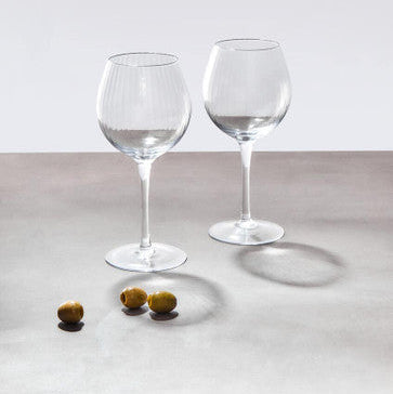 Clear glass gin glasses from the mila set with slender stems and rounded bowls on a light gray surface