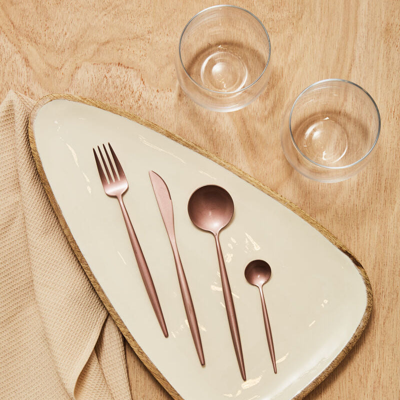 Rose gold flatware set on cream plate with woven edge beside mila set of 2 glass tumblers with wide bowl design