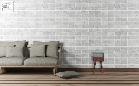 Gray linen sofa with wooden legs and pillows next to a solid mango wood mini cherry bedside table against white brick wall