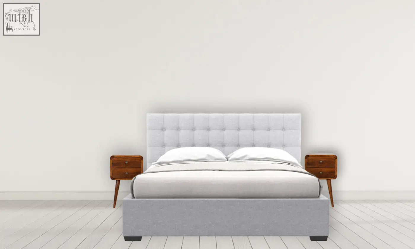 Gray upholstered bed with tufted headboard and matching platform base next to a solid mango wood curved bedside table