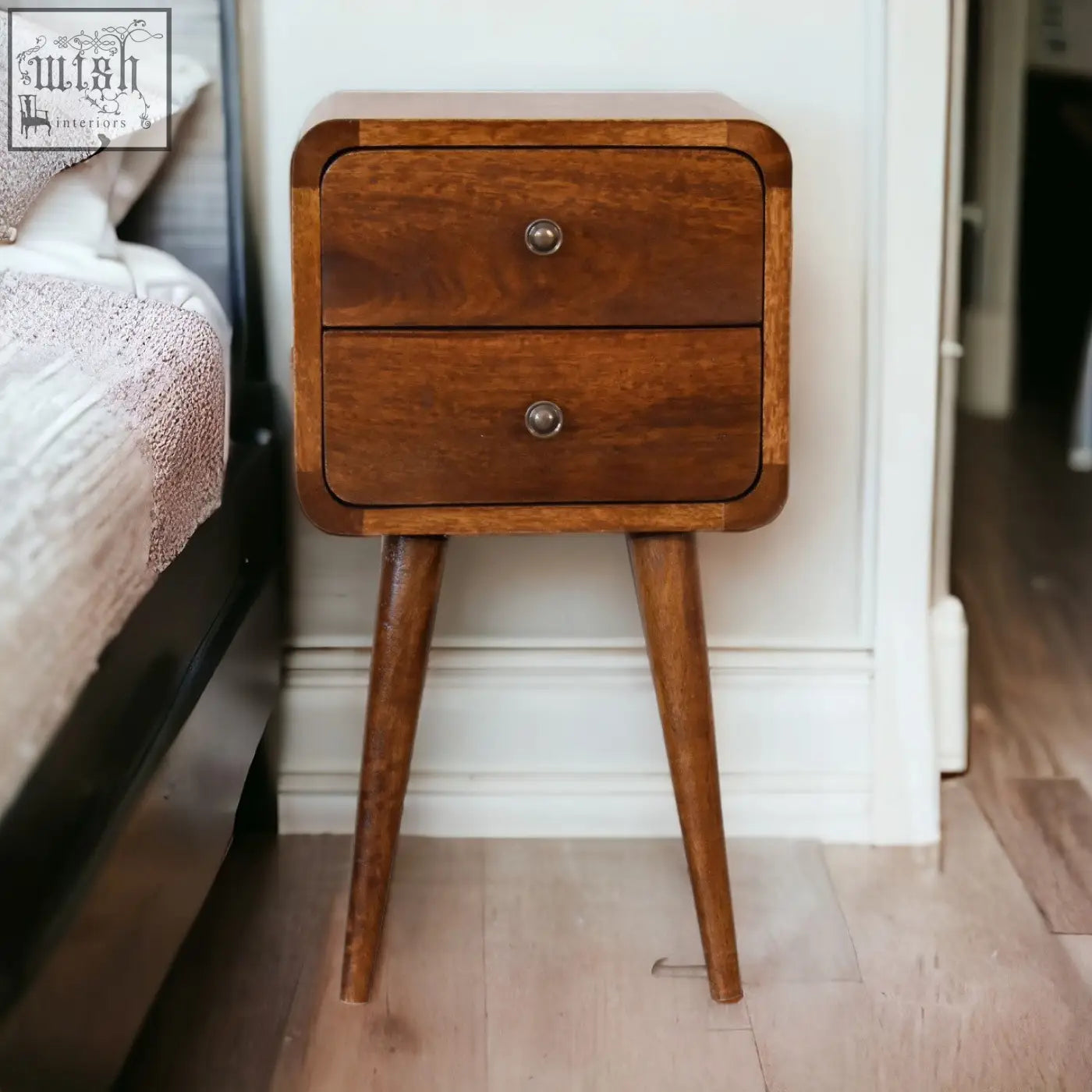 Mini chestnut curved bedside table in warm brown solid mango wood with two drawers and tapered legs