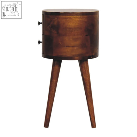 A sleek mini chestnut rounded bedside table in rich brown wood with a cylindrical shape and three tapered legs