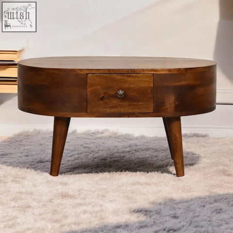 A sleek mini chestnut rounded coffee table with oval shape, tapered legs, single drawer, and wooden finish