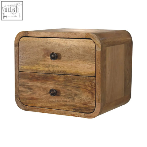 A rustic mini curve floating bedside table in solid mango wood with two drawers and dark metal knobs