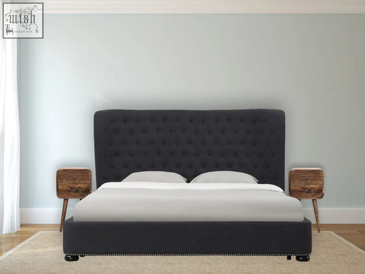 Black tufted velvet headboard with nailhead trim next to a mini curved grey washed solid mango wood bedside table