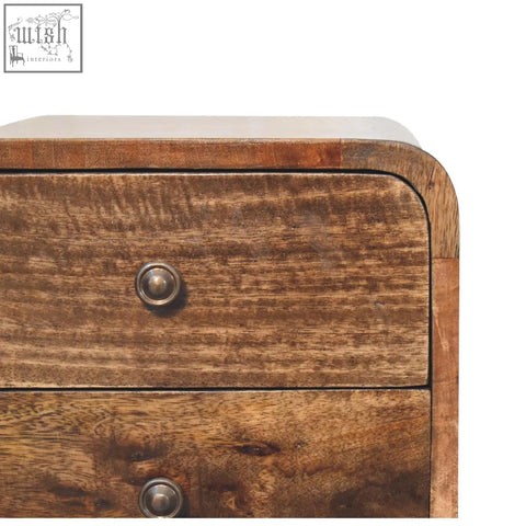 A mini curved grey washed bedside table made of solid mango wood with two drawers and round metallic knobs