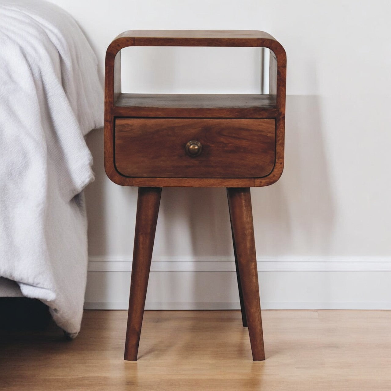 A sleek honey caramel wooden mini bedside table with a curved design open slot and single drawer in dark brown