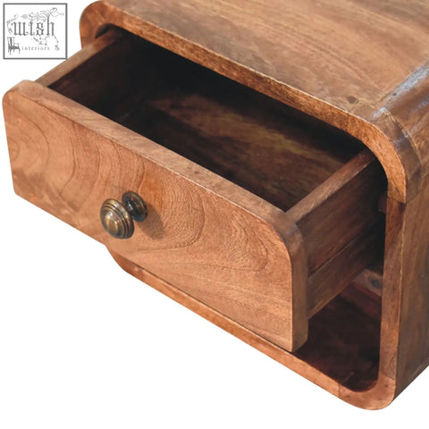A warm-toned honey caramel mango wood mini bedside with curved front, open slot, and antique brass knob drawer