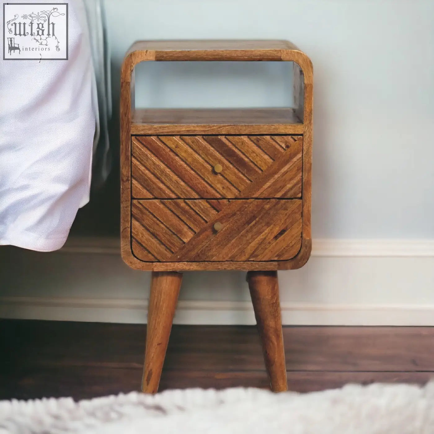 A mid-century modern mini lille curved bedside table in solid oak mango wood with two drawers and an open shelf