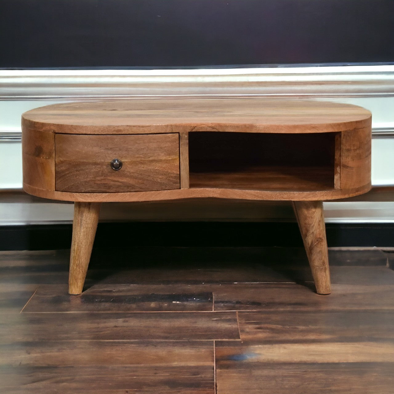 A rustic mini oak-ish wave coffee table with a single drawer open shelf light brown wood and tapered legs