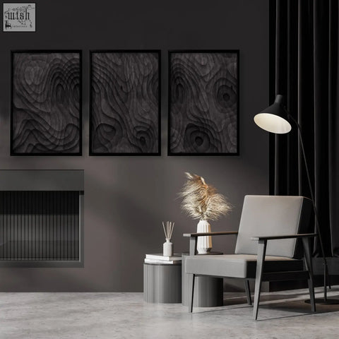 Gray upholstered armchair with dark wooden frame paired with minimalist art dark charcoal topographic wave art prints set of 3