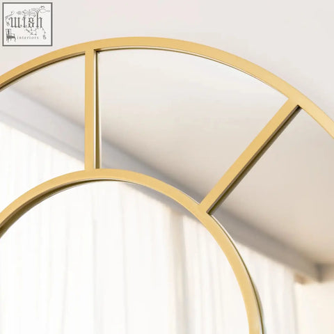 Gold metal framed circular window mirror with segmented glass panes and metal arched design for full length use
