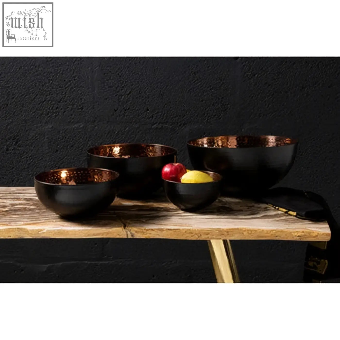 Set of four miressa small hammered black ceramic bowls with copper-finished interiors on rustic wooden table