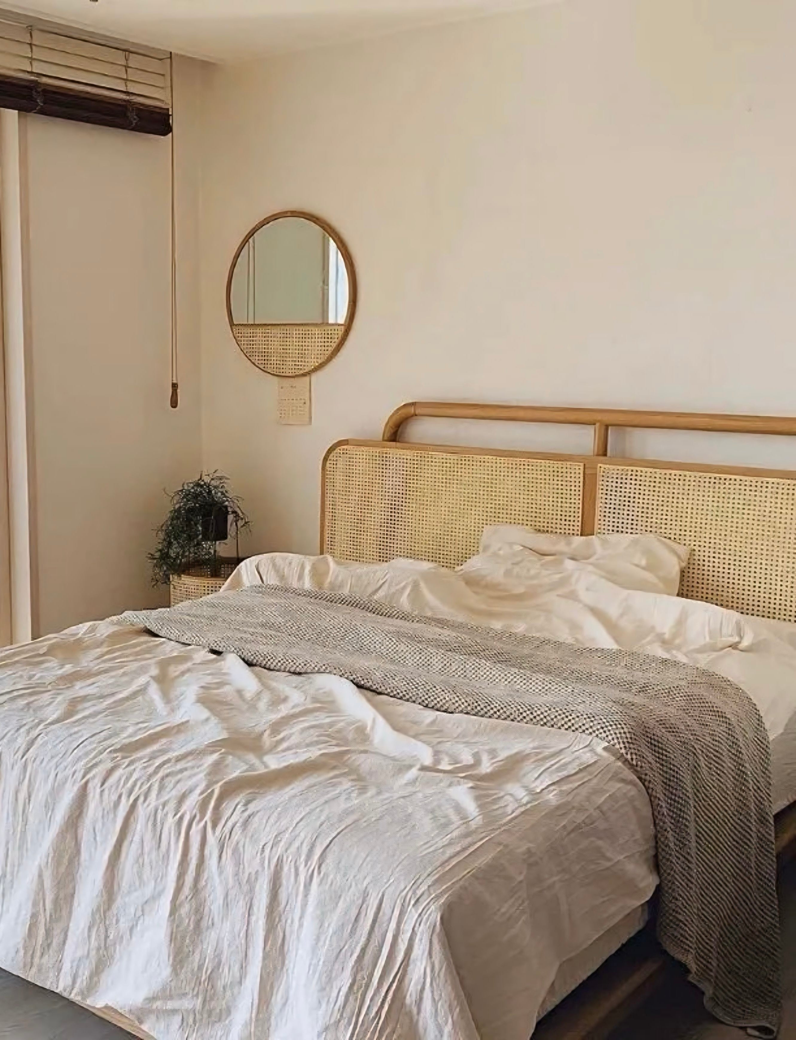 Rattan bed frame with woven cane headboard and light wood trim featured in the mitsuru mirror product line