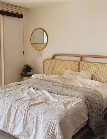 Rattan bed frame with woven cane headboard and light wood trim featured in the mitsuru mirror product line