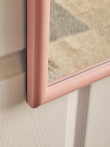 A sleek mize pink plastic frame over door mirror with a matte pink plastic frame mounted on a white wall