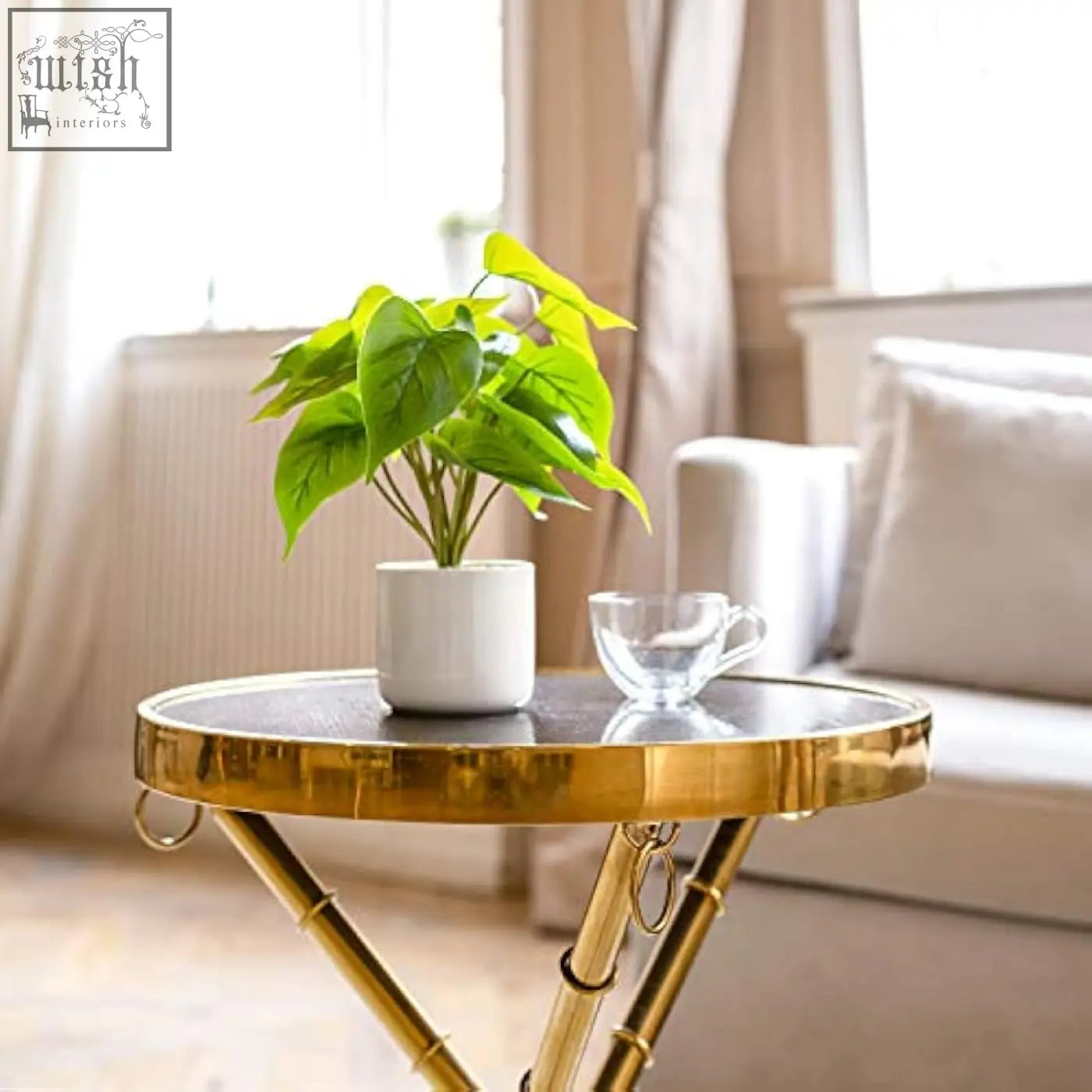 A vibrant artificial pothos potted plant with green leaves in a modern white ceramic pot on a gold side table