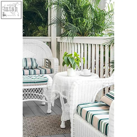 White wicker patio set with green and beige striped cushions next to a potted artificial pothos in a ceramic pot