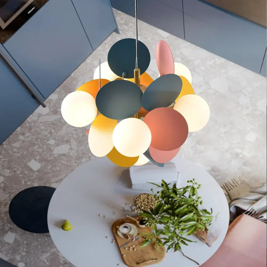 A modern led chandelier with colorful matte pastel and dark circular shades as a stylish light source above a round table