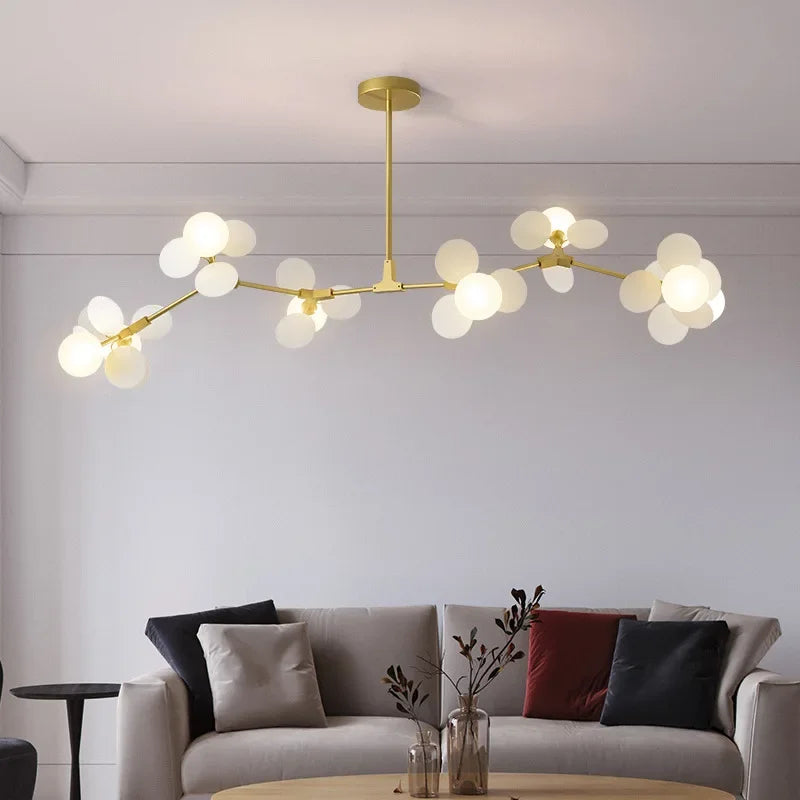 Modern led chandelier with gold-toned branching arms and frosted glass globe bulbs as light source for luxury ceiling light