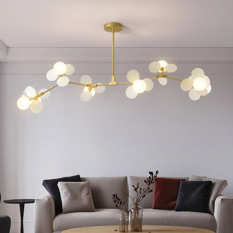 Modern led chandelier with gold-toned branching arms and frosted glass globe bulbs as light source for luxury ceiling light