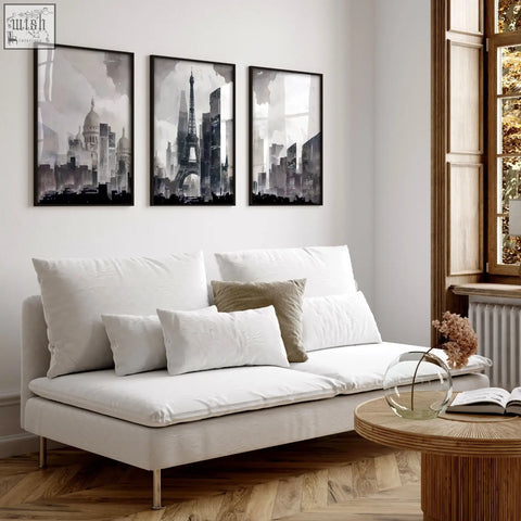 White upholstered sofa with metallic legs and cushions in modern living room featuring paris skyline grey wall art set