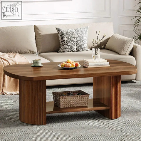 Modern oval walnut coffee table with warm wood oval top fluted pedestal base and open shelf holding woven basket