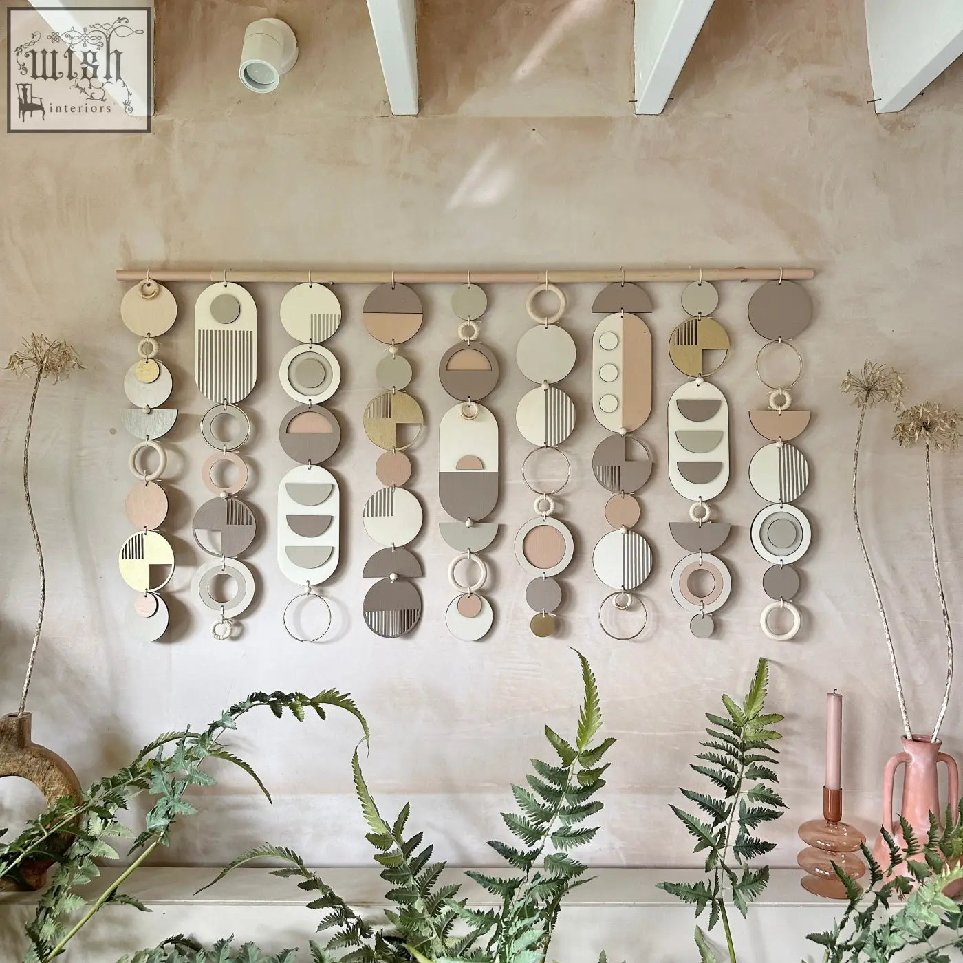 A modern wall art piece featuring layered earth toned wooden circles and rectangles with minimalist patterns