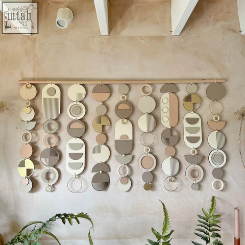 A modern wall art wooden geometric wall hanging with circular and oval shapes in muted earth tones for home decor