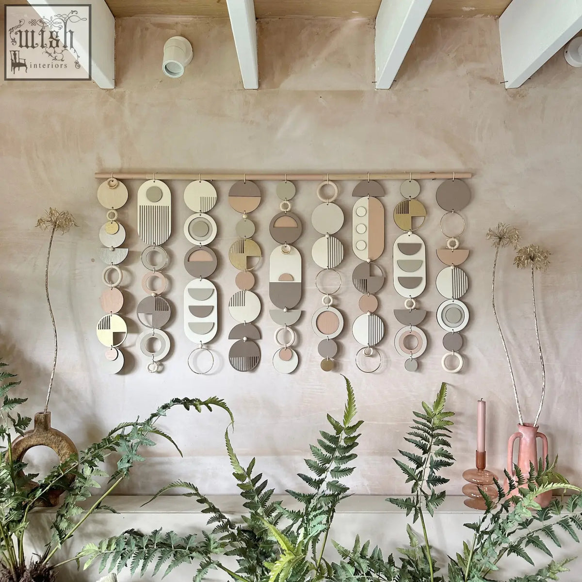 Modern wall art featuring layered circular and oval shapes in muted earth tones crafted from painted wood or ceramic