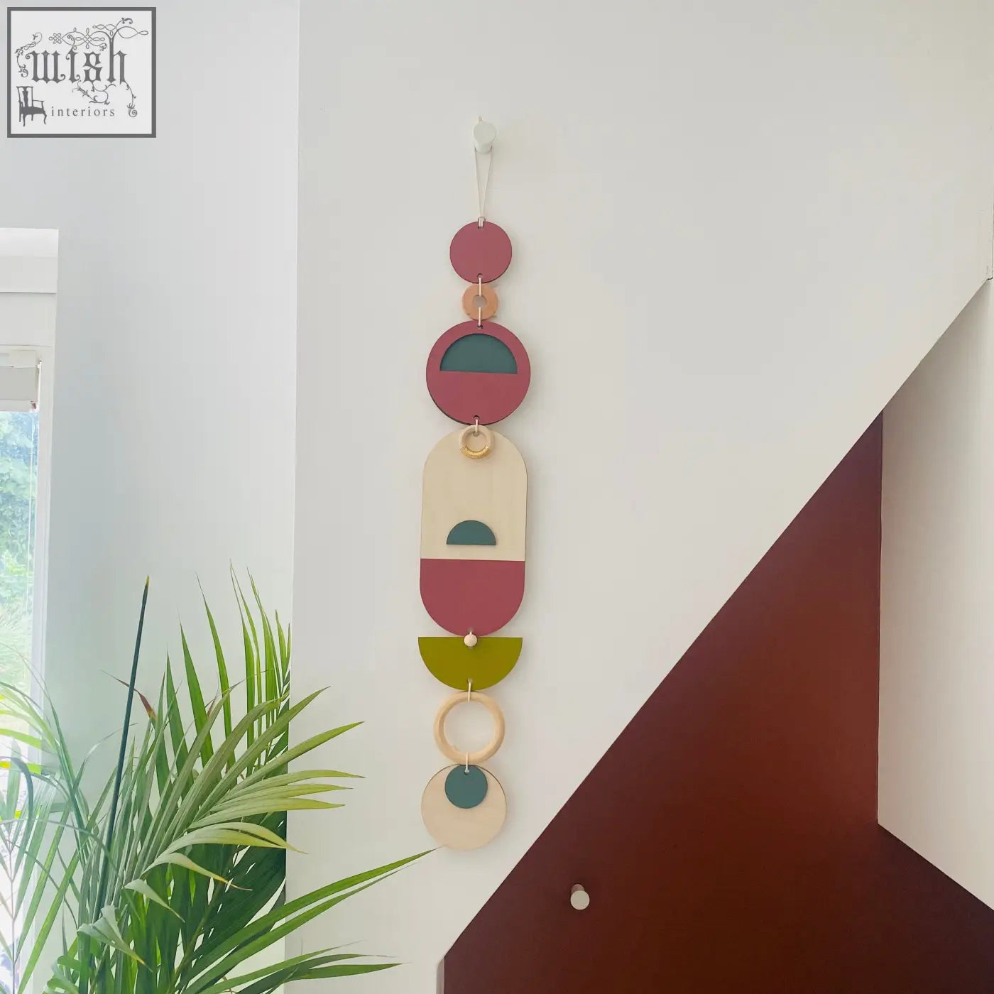 A modern wall art piece featuring layered circular and oval shapes in terracotta sage green cream and natural wood tones