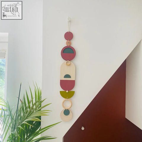 A modern wall art piece featuring layered circular and oval shapes in terracotta sage green cream and natural wood tones