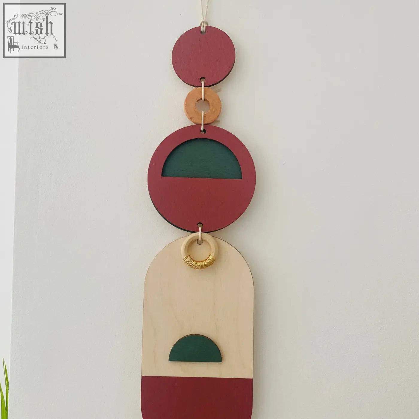Modern wall art featuring a geometric wooden design in red beige and green with a natural wood ring accent