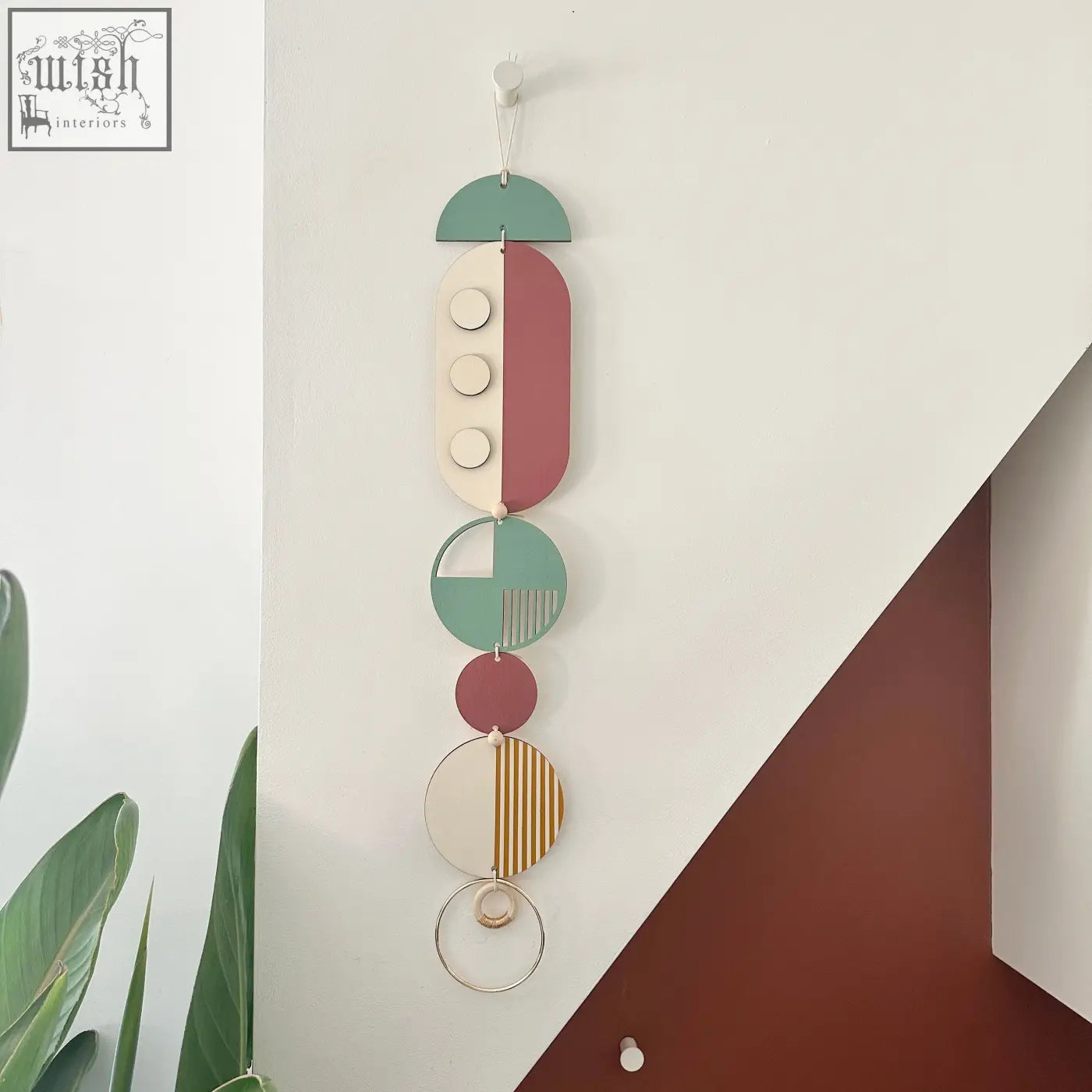 Modern wall art featuring stacked circular and oval shapes in muted green terracotta cream and gold wood decor