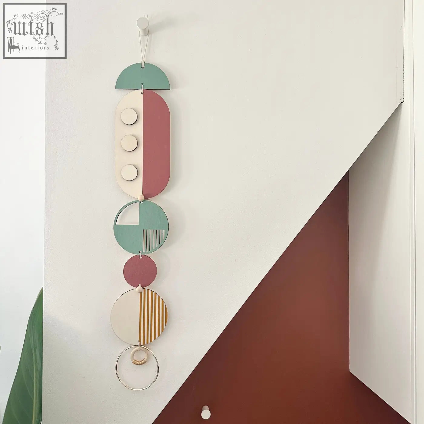 A modern wall art featuring layered wooden discs in teal blush pink cream and gold with subtle patterns