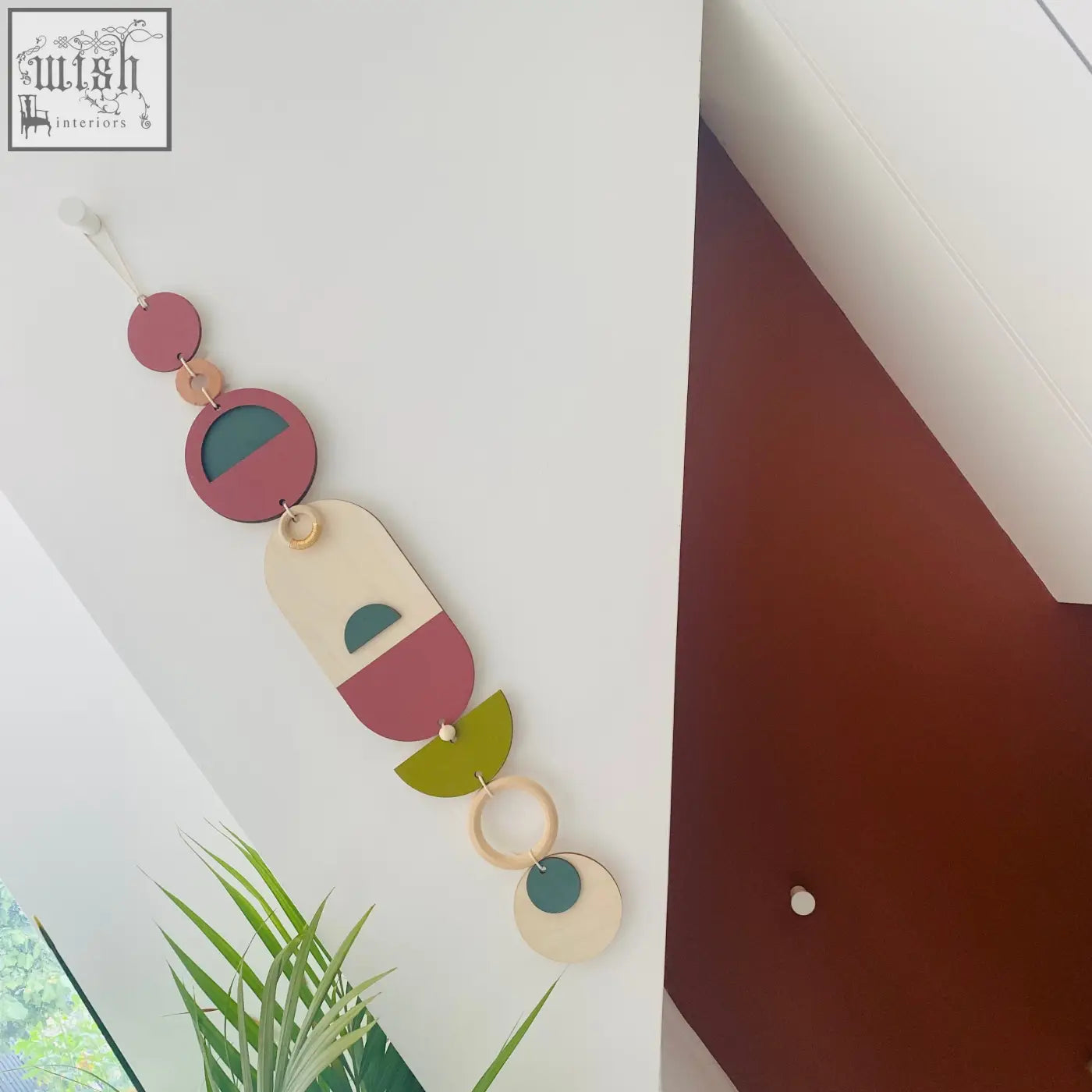 A modern wall art piece featuring layered circular shapes in muted pink olive green cream and teal tones for minimal decor