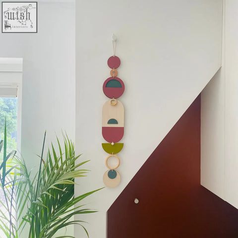 A modern wall art vertical wooden hanging with layered dusty rose olive green and cream geometric shapes