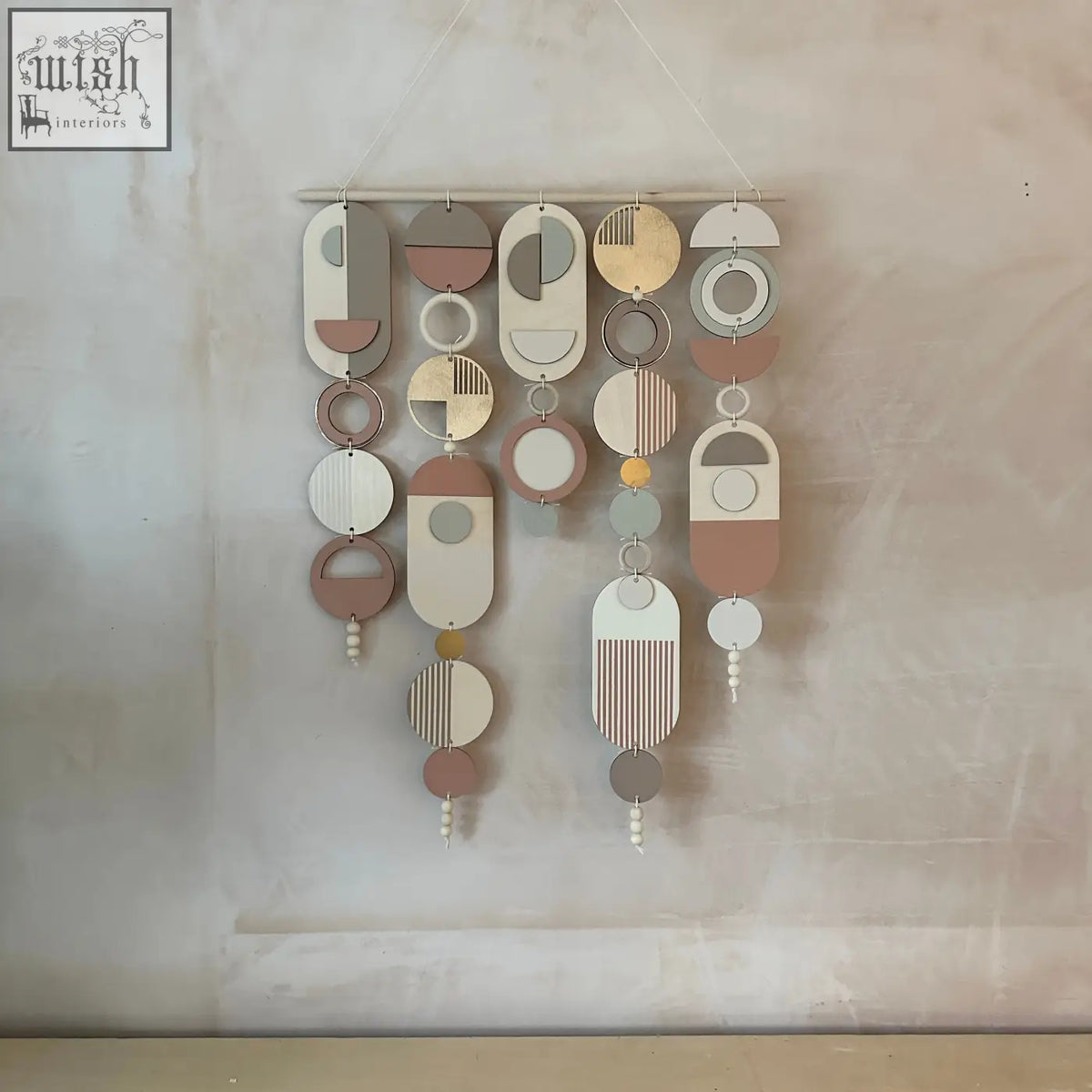 Modern wall art with gold metal hoop detailing featuring layered wooden and painted metal pieces with pink accents