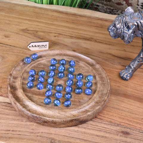 Blue faceted glass marbles on a round wooden tray in the moksha deluxe solitaire board game set