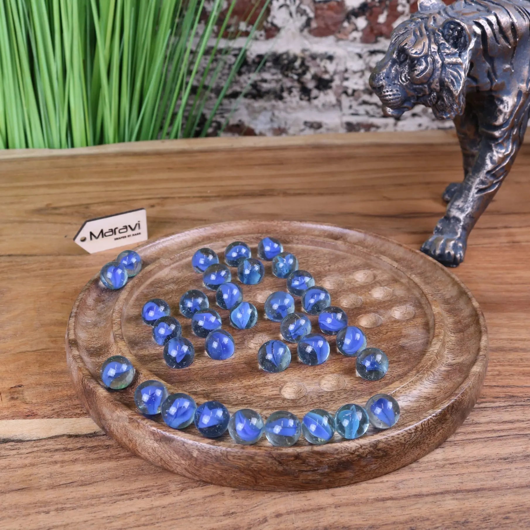 Blue translucent glass marbles on a round wooden board in the moksha deluxe solitaire board game set