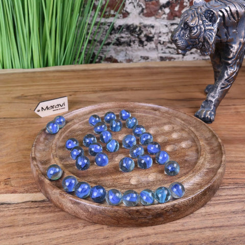 Blue translucent glass marbles on a round wooden board in the moksha deluxe solitaire board game set