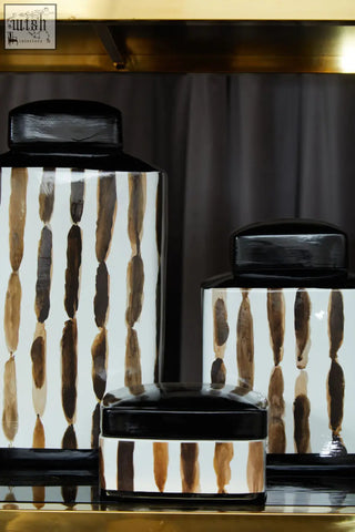 Set of three small ceramic jars with white bodies brown brushstroke patterns and glossy black lids perfect for storage