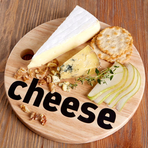 Round wooden mono cheese board with hole featuring creamy white-rinded and blue-veined cheese with crackers pears and walnuts