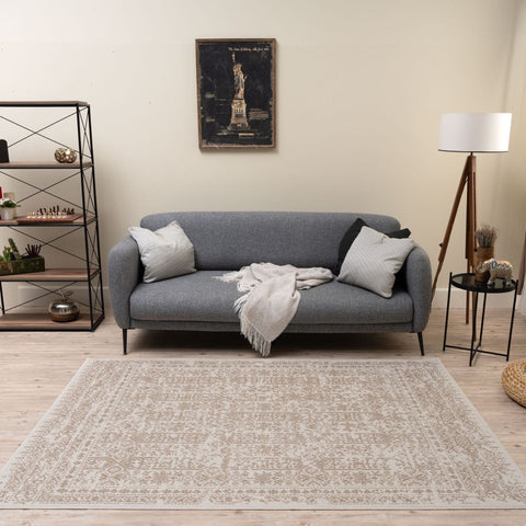 Gray upholstered sofa with striped pillows and a textured throw blanket on montana cream and beige rug 3716cb
